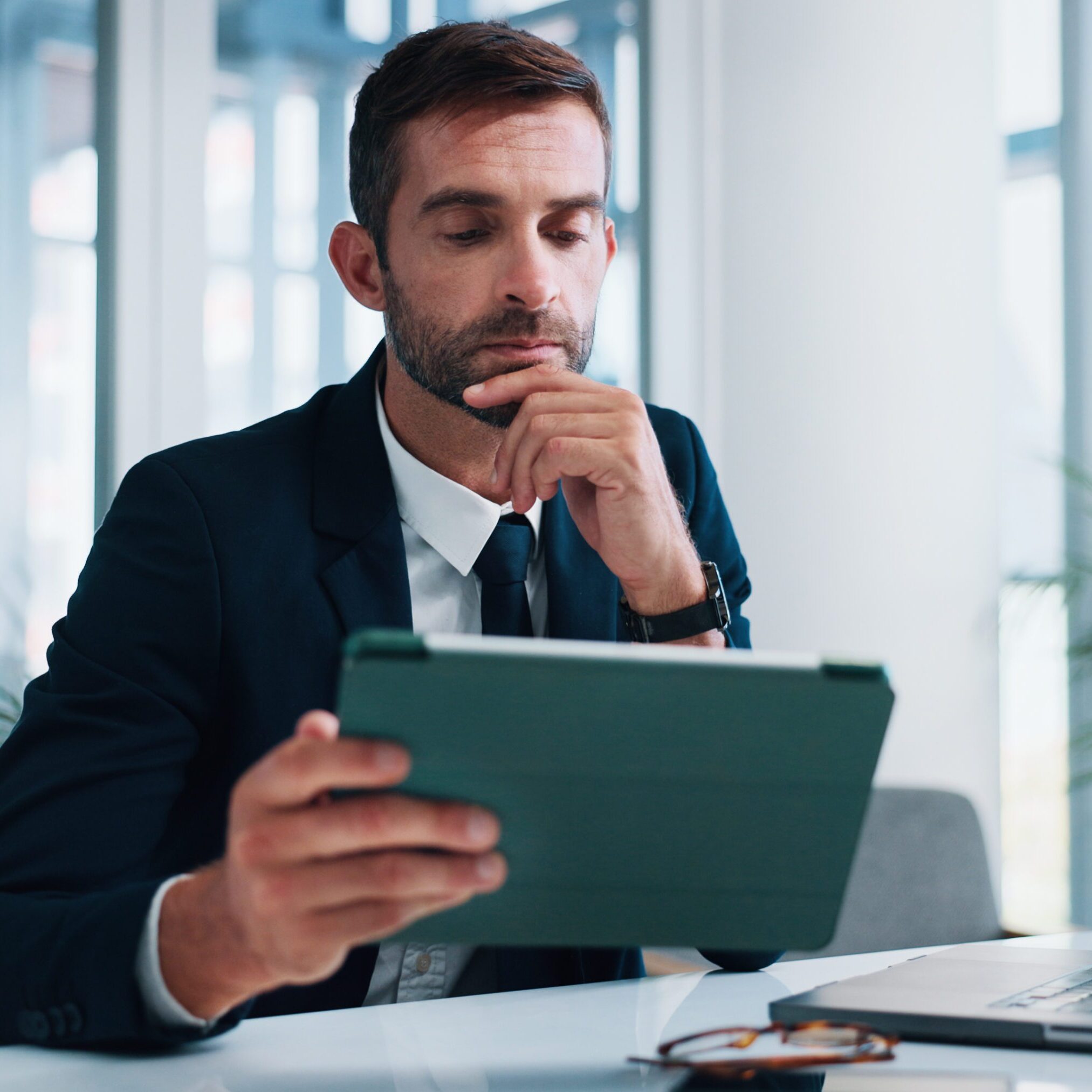 Man, lawyer and tablet with thinking in office for research, decision or review evidence for tax fraud case. Person, attorney and touchscreen with financial crime, info and app at corporate law firm